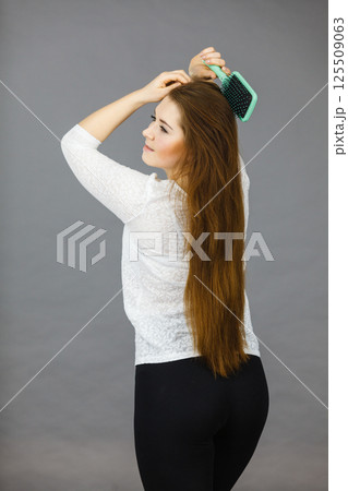 Happy woman brushing her hair Happy woman brushing her hair 125509063