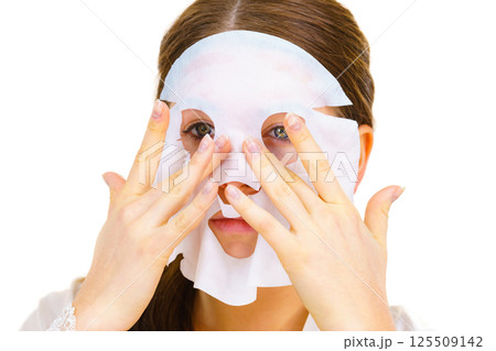 Woman applying sheet mask on face 125509142