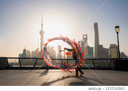 Silhouette Chinese man show ribbon dance at the Bund, Shanghai Silhouette Chinese man show ribbon dance at the Bund, Shanghai 125510361