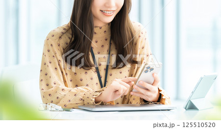 スマートフォンを使う笑顔の女性・ビジネスウーマン 125510520