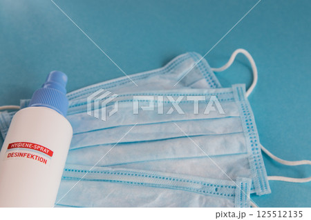Desinfection spray and medical mask for hygiene on the blue background with place for text. Antibacterial, against pollution or virus protection. Coronavirus infection.  125512135