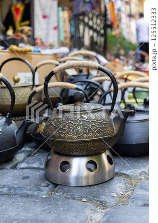 Traditional asian teapots displayed on metal stand in outdoor market 125512333