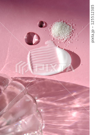 Beauty products on a pink background with highlights from the water. 125512385