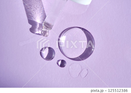 A drop of serum with a pipette on a purple background. 125512386