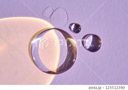 A drop of serum or micellar water on a purple background. 125512390