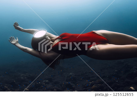 Gorgeous woman freediver in red swimwear swims underwater in deep ocean. Sexy woman freediving. 125512655