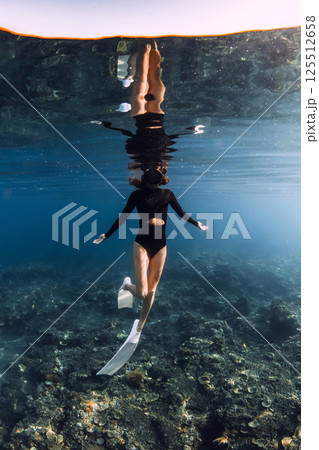 Woman freediver swimming underwater in blue ocean on the reef. Vertical shot 125512658