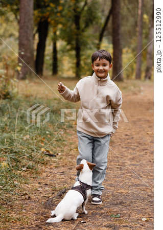 Asian Boy Playing with Dog in Autumn Forest 125512990