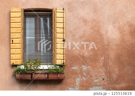 Rustic window with wooden shutters and flower box on weathered wall Rustic window with wooden shutters and flower box on weathered wall 125513619