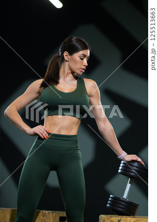 focused athlete lifts dumbbell while showcasing strength and determination. setting features contemporary gym environment vibrant atmosphere and supportive elements. 125513663