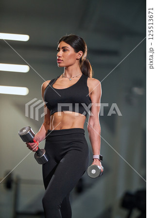 fitness enthusiast is performing workout in gym setting confidently holding dumbbells while showcasing athletic physique. environment features modern equipment and well lit backdrop. fitness enthusiast is performing workout in gym setting confidently holding dumbbells while showcasing athletic physique. environment features modern equipment and well lit backdrop. 125513671