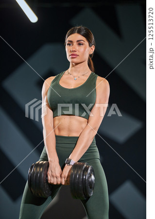 athletic individual exercises heavy dumbbell in contemporary gym. 125513720