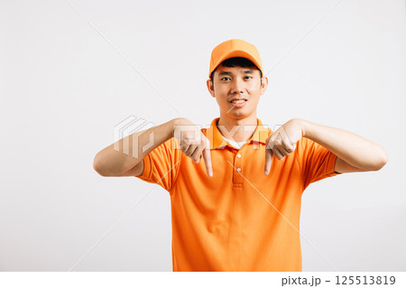 Portrait Asian smiling young delivery man pointing down something with empty space hands studio isolated white background, Happy lifestyle men carry person in an orange shirt uniform point finger 125513819
