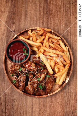 barbecue chicken wings, sprinkled with sesame seeds, with French fries, and sauce, on a wooden plate, rustic style, barbecue chicken wings, sprinkled with sesame seeds, with French fries, and sauce, on a wooden plate, rustic style, 125513932