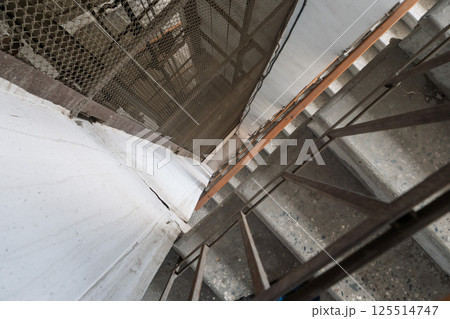 Concrete staircase with metal handrail in decaying abandoned building creates eerie atmosphere 125514747