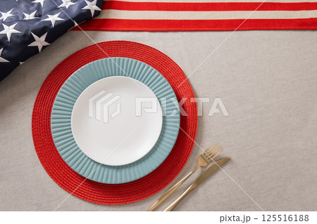Table setting for USA Independence Day. Festive dinner with empty white plate and decoration in USA national flag colors red and blue. View from above. Copy space. Close up. 125516188