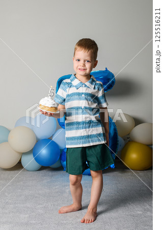 Happy Five Year Old Boy Celebrating Birthday with Cupcake and Candle 125516211