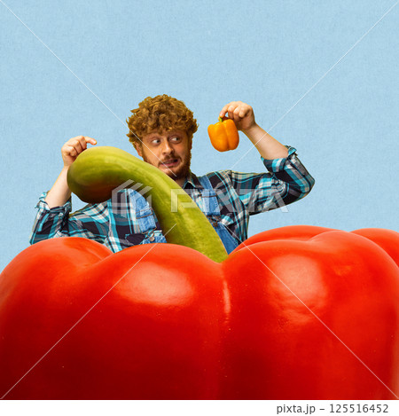 Farmer man compares giant red pepper and small yellow pepper against blue background Farmer man compares giant red pepper and small yellow pepper against blue background 125516452