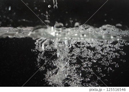 Water splashing as it's poured into aquarium tank, black background Water splashing as it's poured into aquarium tank, black background 125516546