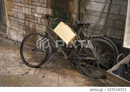 Unused rusty old black bicycle with wooden box parked near dirty brick wall 125516551