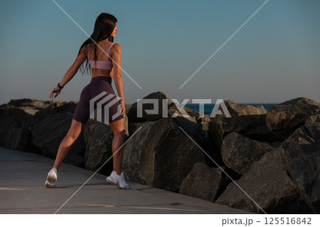 woman is exercising stretching water's edge sunset. glowing sky and tranquil sea create peaceful atmosphere for her wellness routine. woman is exercising stretching water's edge sunset. glowing sky and tranquil sea create peaceful atmosphere for her wellness routine. 125516842