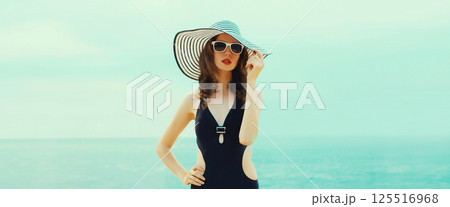 Summer beautiful young woman in bikini swimsuit, black hat, stylish girl posing on the beach on sea 125516968