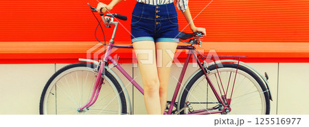 Summer image of legs of beautiful young woman in shorts posing with bicycle in the city 125516977