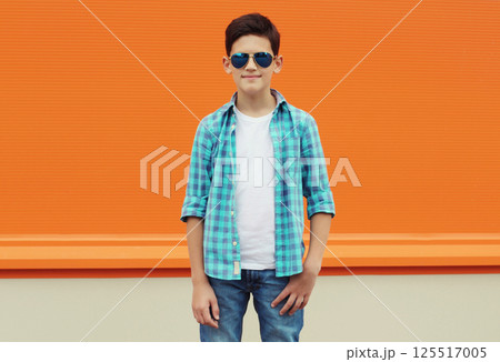Modern teenage kid boy in casual clothes with glasses standing on city street 125517005