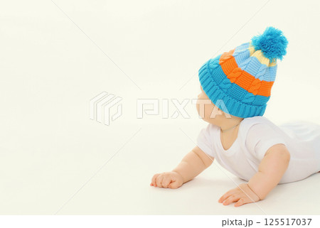 Happy baby in winter knitted hat crawling on the floor playing on white studio background Happy baby in winter knitted hat crawling on the floor playing on white studio background 125517037