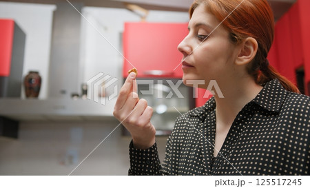 Happy Woman Eats Sweet Cantucci In Kitchen 125517245