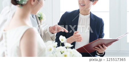 新郎新婦と話す結婚式場スタッフ 新郎新婦と話す結婚式場スタッフ 125517365