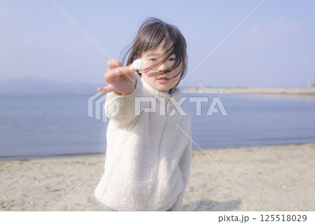 ガラスの砂浜で貝殻を手に持っている女の子 ガラスの砂浜で貝殻を手に持っている女の子 125518029