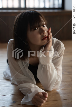 フローリングに寝転ぶクールな若い女性 フローリングに寝転ぶクールな若い女性 125518356