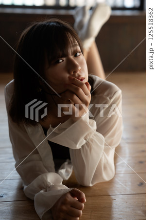 フローリングに寝転ぶクールな若い女性 125518362