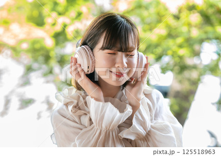 新緑が見える部屋で音楽を聴く若い女性 新緑が見える部屋で音楽を聴く若い女性 125518963