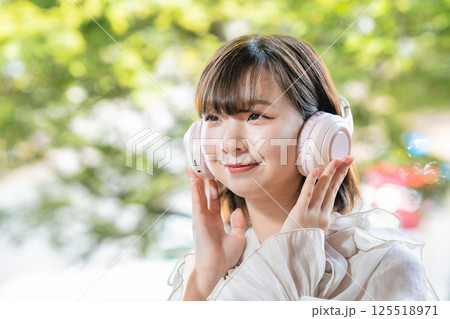 新緑が見える部屋で音楽を聴く若い女性 新緑が見える部屋で音楽を聴く若い女性 125518971