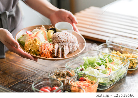 キッチンでワンプレートランチを盛り付ける主婦の手元 125519560