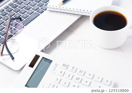 淹れたてのコーヒーを飲みながら、ノートパソコンと電卓でデスクワークをしているイメージ 淹れたてのコーヒーを飲みながら、ノートパソコンと電卓でデスクワークをしているイメージ 125519800
