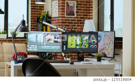 Clean modern desk setup in a living room designed for media production, video post production. Dual monitors display video editing software, tech tools and a color wheel add a professional touch. Clean modern desk setup in a living room designed for media production, video post production. Dual monitors display video editing software, tech tools and a color wheel add a professional touch. 125519804