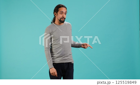 Salesman pointing around with finger, doing recommendation, talking with audience. Man showing copy text space, doing advertisement, isolated over studio background, camera A Salesman pointing around with finger, doing recommendation, talking with audience. Man showing copy text space, doing advertisement, isolated over studio background, camera A 125519849