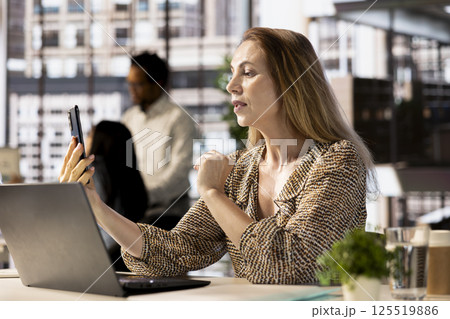 Company manager multitasking during a video call meeting with investors, balancing administrative tasks and project objectives. Fostering online communication for remote business partnerships. Company manager multitasking during a video call meeting with investors, balancing administrative tasks and project objectives. Fostering online communication for remote business partnerships. 125519886