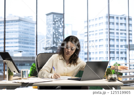 Female leader with executive power signing work contracts and approving employees requests, doing daily paperwork tasks for productivity. Giving authorization for leave request or license agreement. 125519905