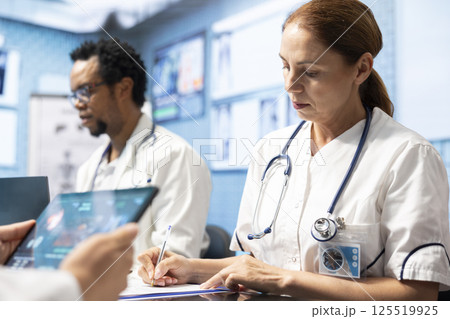 Group of diverse doctors in a treatment center reviewing brain scan results, examining neurology mri tests. Experts collaborate on diagnostics, treatment plans and disease prevention. Tomography Group of diverse doctors in a treatment center reviewing brain scan results, examining neurology mri tests. Experts collaborate on diagnostics, treatment plans and disease prevention. Tomography 125519925