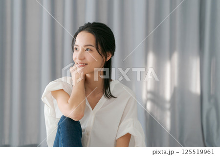 カーテンの前で微笑む女性 125519961