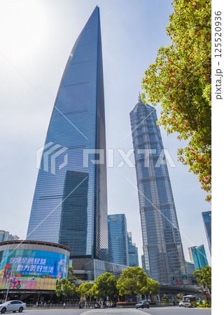 Shanghai, China - 1 April 2025: Futuristic Pudong skyline featuring Shanghai World Financial Center and Jin Mao Tower with bustling streets below on a sunny day 125520936