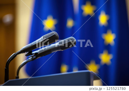 Wooden podium with two microphones against EU flag backdrop. Platform for speech presentation at government press conference, politic debates. 125521780