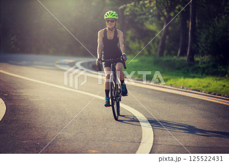 Woman cyclist riding bike at summer park Woman cyclist riding bike at summer park 125522431