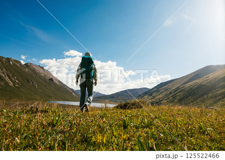 Woman backpacker hiking on high altitude mountain top,with a lake in the distance Woman backpacker hiking on high altitude mountain top,with a lake in the distance 125522466