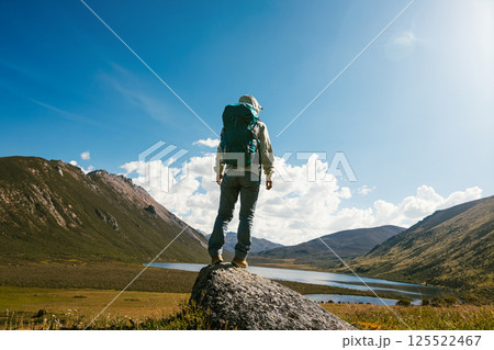 Woman backpacker hiking on high altitude mountain top,with a lake in the distance Woman backpacker hiking on high altitude mountain top,with a lake in the distance 125522467