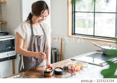 キッチンでお弁当を詰める若いアジア人女性(お母さん・妻・主婦) キッチンでお弁当を詰める若いアジア人女性(お母さん・妻・主婦) 125523134